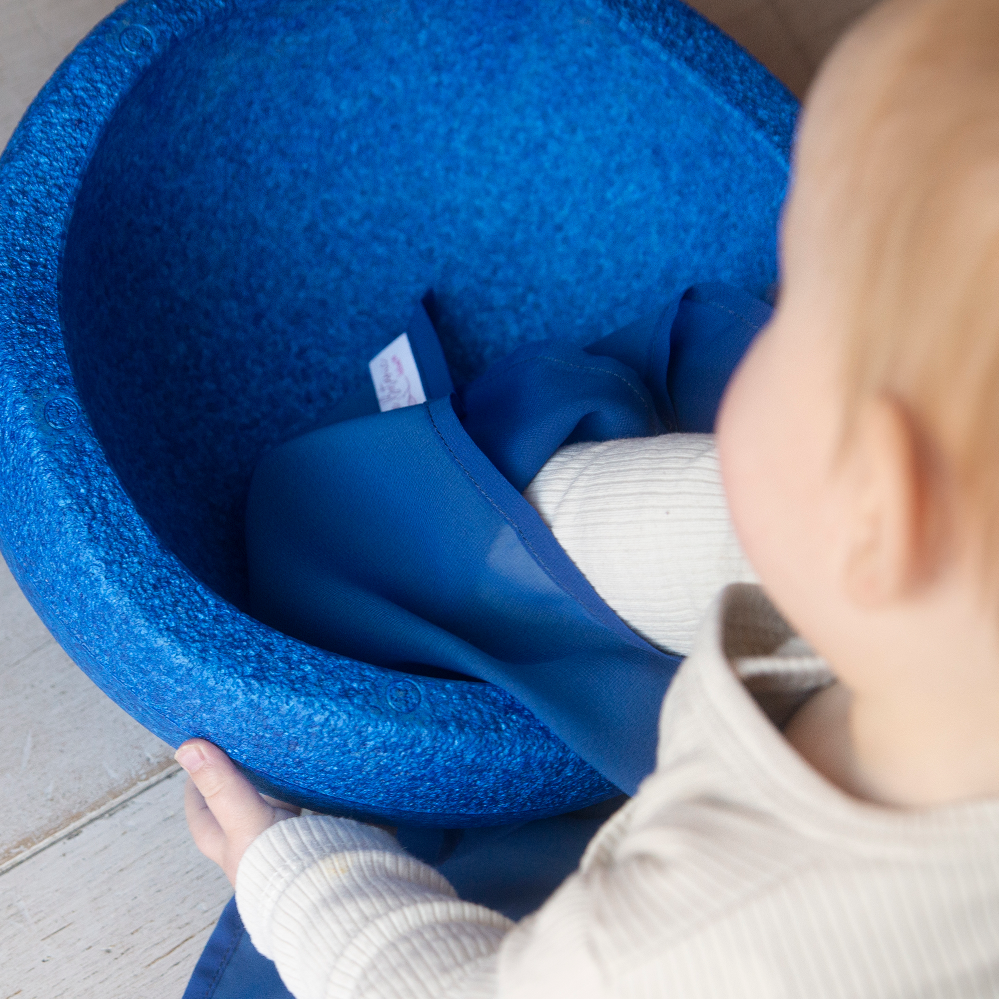 dreumes speelt met blauwe stapelstein en speeldoek